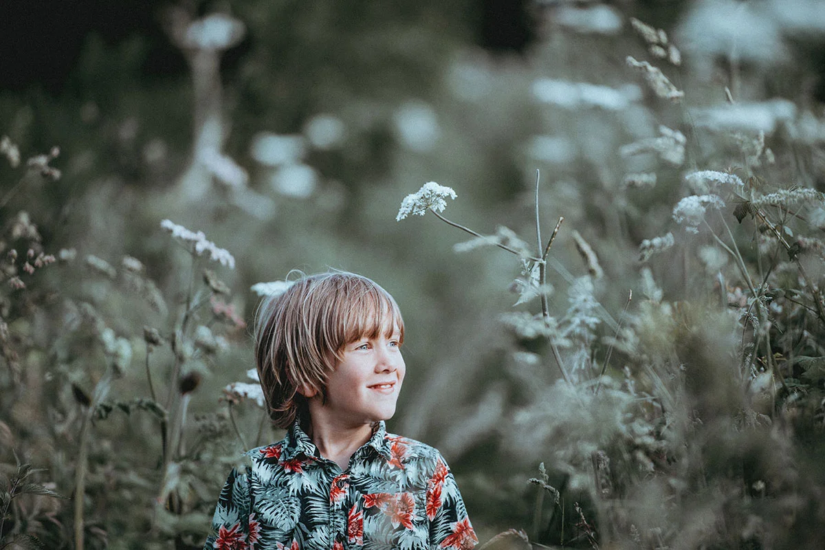 Hymyilevä poika seisoo pellolla.